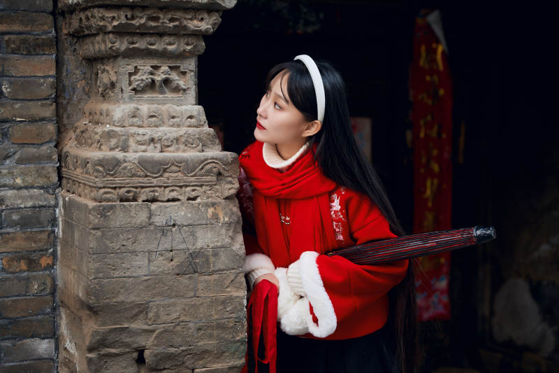 雪后在老城古巷穿着喜庆服饰的亚洲少女图片