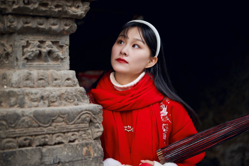 雪后在老城古巷穿着喜庆服饰的亚洲少女图片