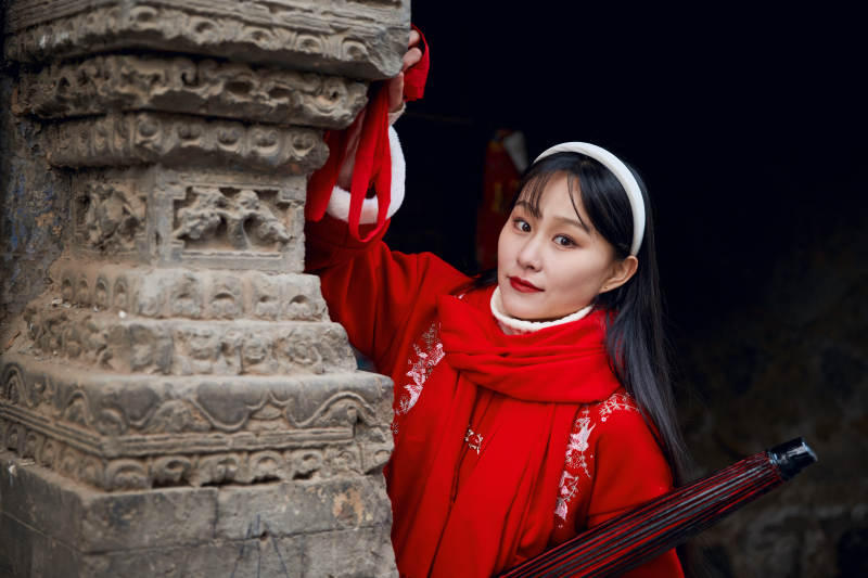 雪后在老城古巷穿着喜庆服饰的亚洲少女图片