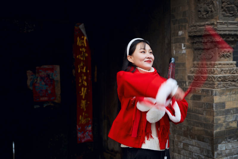 雪后在老城古巷穿着喜庆服饰的亚洲少女图片