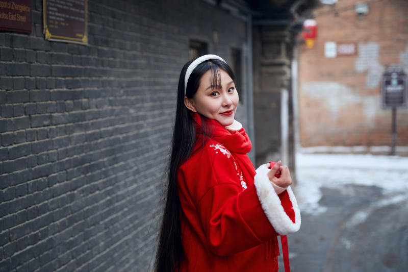 雪后在老城古巷穿着喜庆服饰的亚洲少女图片