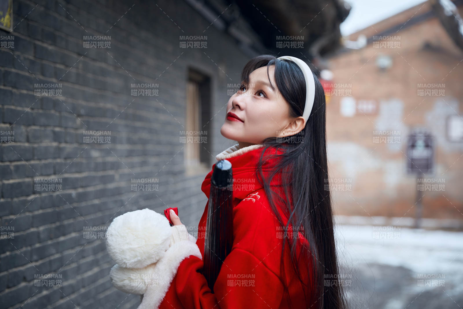 雪后在老城古巷穿着喜庆服饰的亚洲少女图片