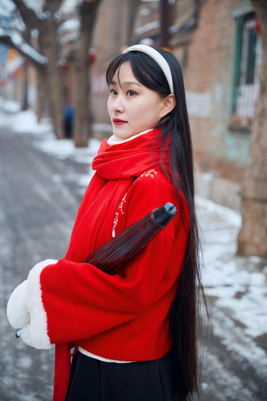 雪后在老城古巷穿着喜庆服饰的亚洲少女图片