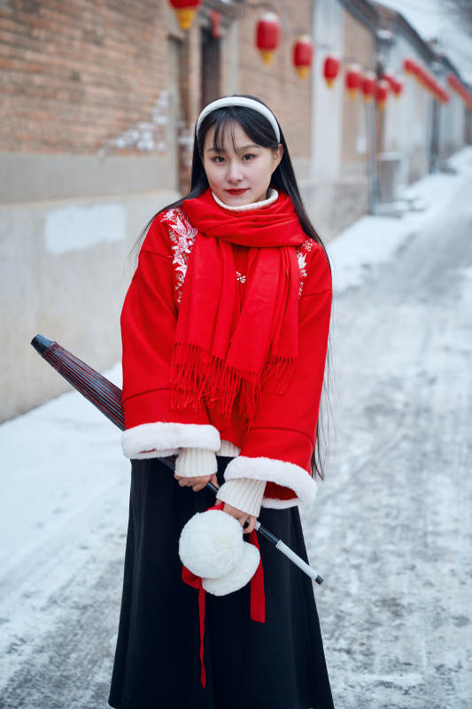 雪后在老城古巷穿着喜庆服饰的亚洲少女图片