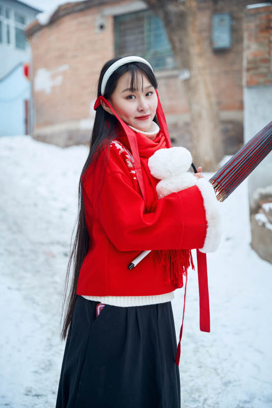 雪后在老城古巷穿着喜庆服饰的亚洲少女图片