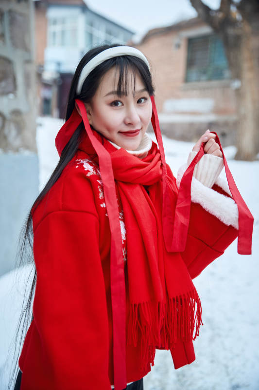雪后在老城古巷穿着喜庆服饰的亚洲少女图片