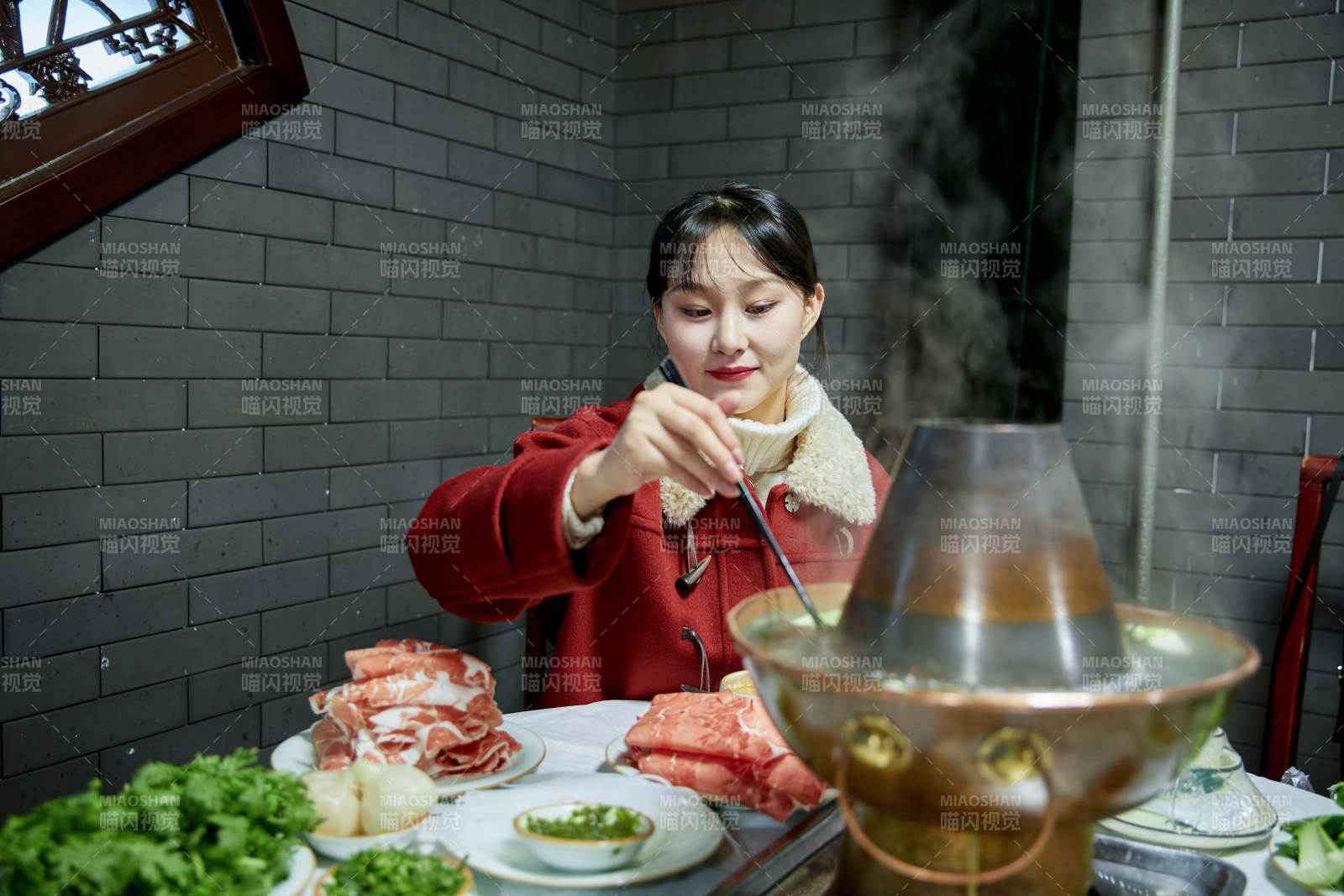 在饭店吃传统铜锅涮肉的亚洲少女图片