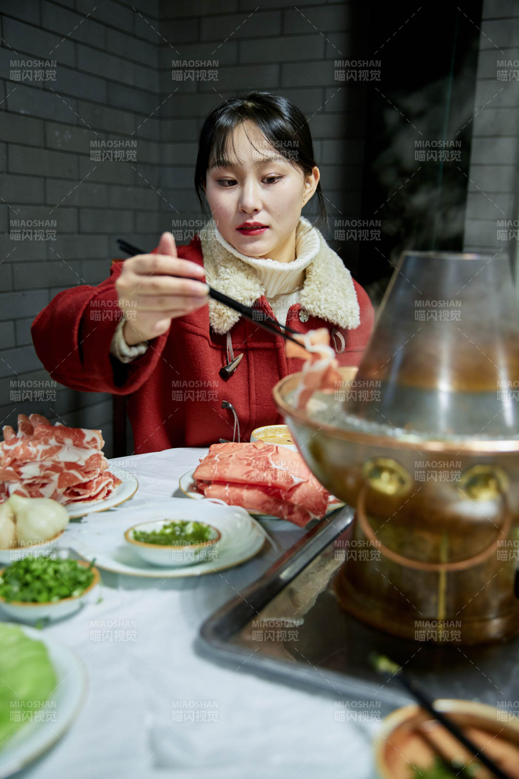 在饭店吃传统铜锅涮肉的亚洲少女图片