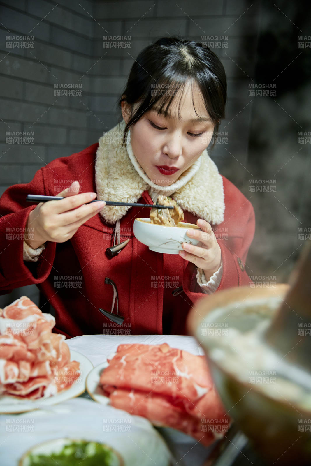 在饭店吃传统铜锅涮肉的亚洲少女图片