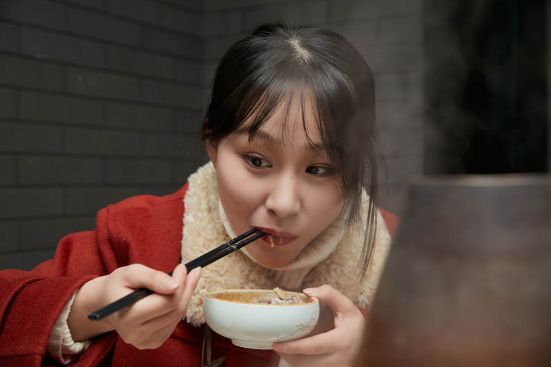 在饭店吃传统铜锅涮肉的亚洲少女图片