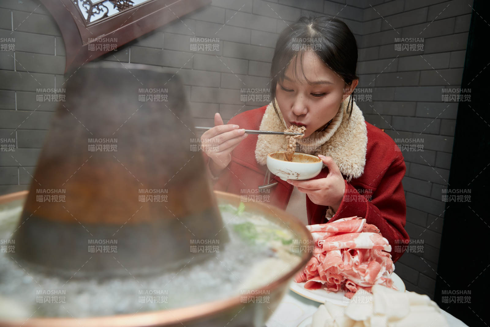 在饭店吃传统铜锅涮肉的亚洲少女图片