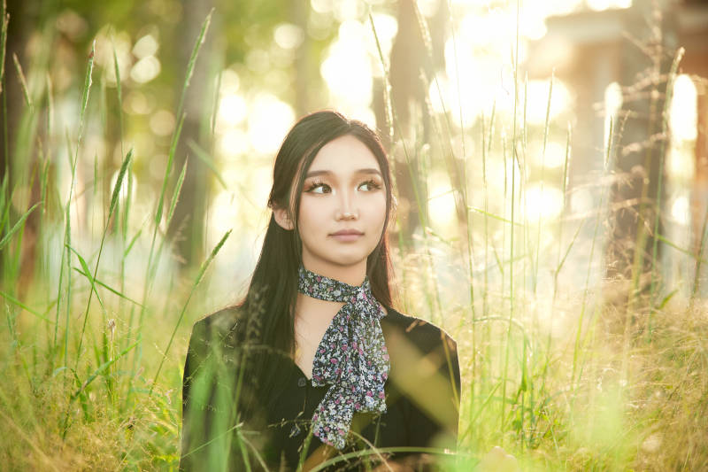 盛夏夕阳照射下花丛草地中的亚洲美女图片