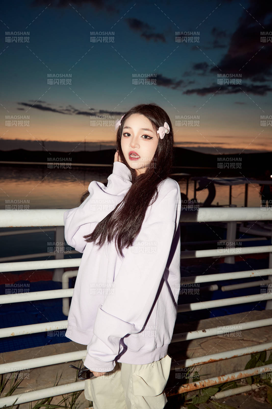 傍晚在湖边欣赏风景拍照的亚洲美女图片