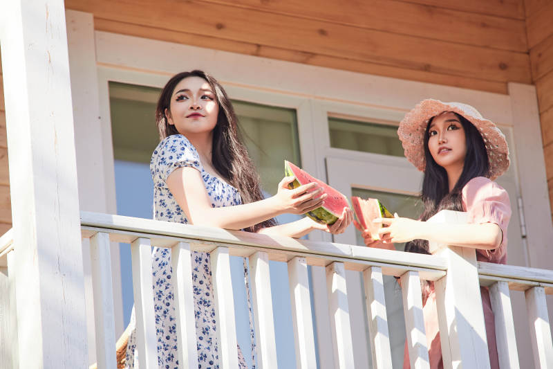 夏天在木质别墅门廊外吃西瓜的美女图片