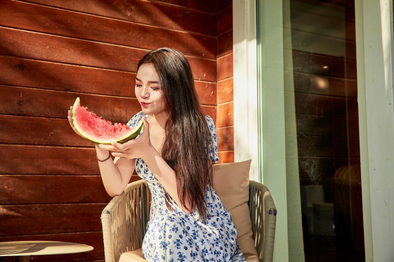 夏天在木质别墅门廊外吃西瓜的美女图片