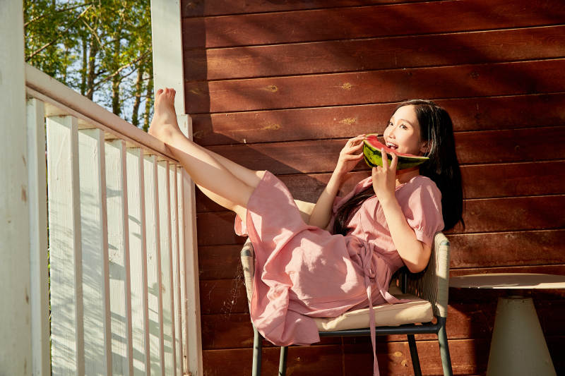 夏天在木质别墅门廊外吃西瓜的美女图片