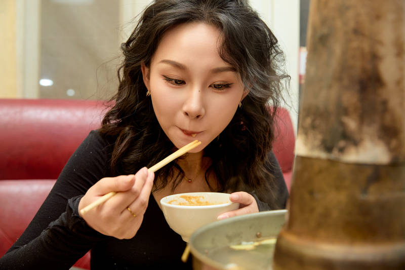 饭店吃传统铜锅涮肉的东方美女图片