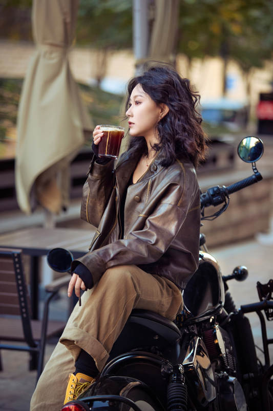 手拿冰美式咖啡坐在摩托上的亚洲美女图片