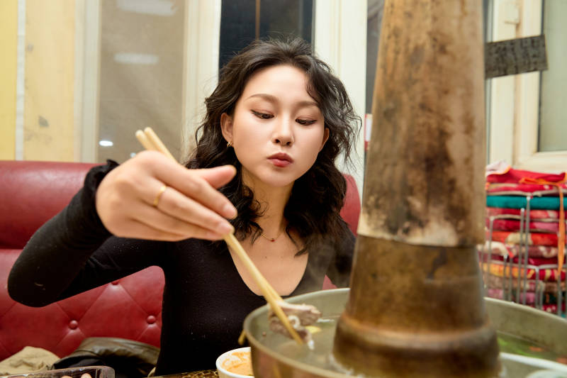 饭店吃传统铜锅涮肉的东方美女图片