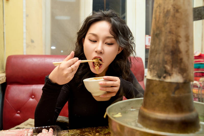 饭店吃传统铜锅涮肉的东方美女图片