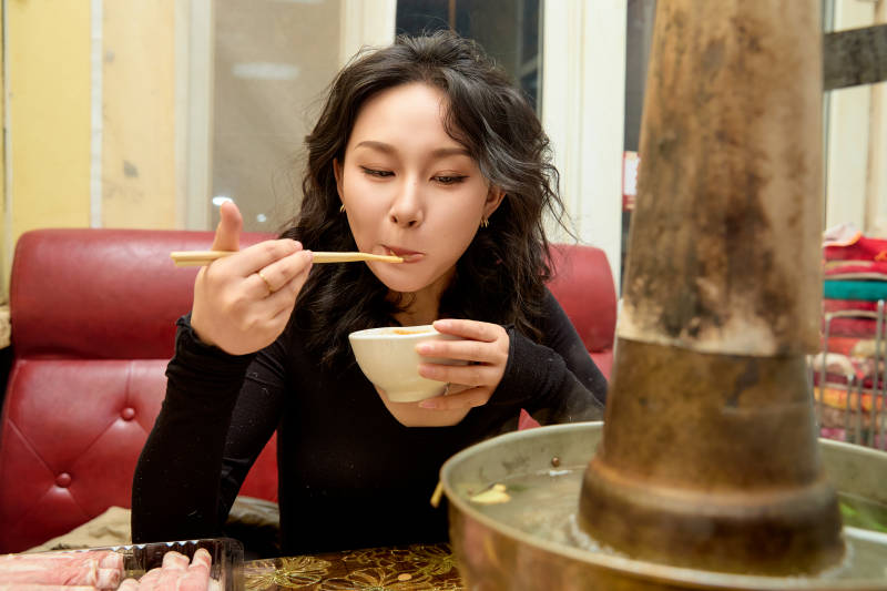 饭店吃传统铜锅涮肉的东方美女图片