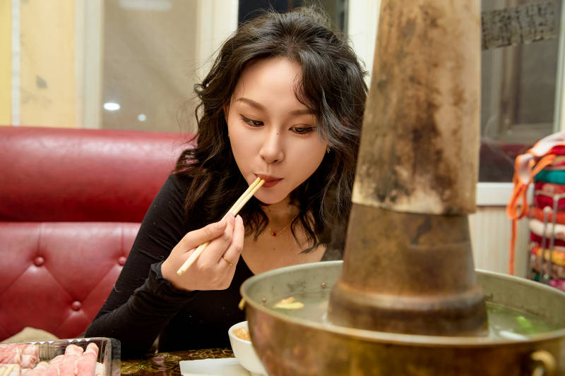 饭店吃传统铜锅涮肉的东方美女图片