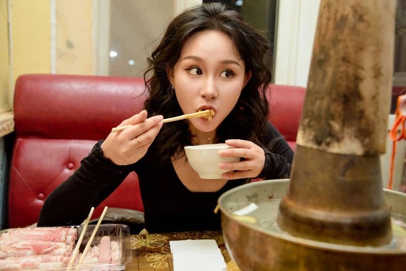饭店吃传统铜锅涮肉的东方美女图片
