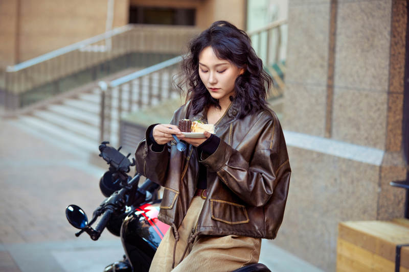 户外在复古机车上品尝甜点的亚洲美女图片