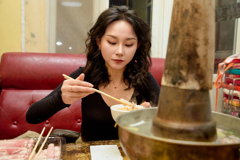 饭店吃传统铜锅涮肉的东方美女图片