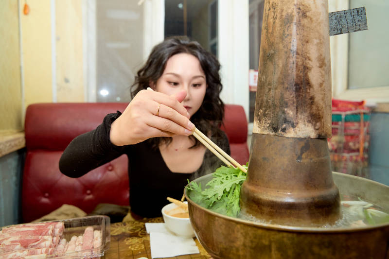 饭店吃传统铜锅涮肉的东方美女图片