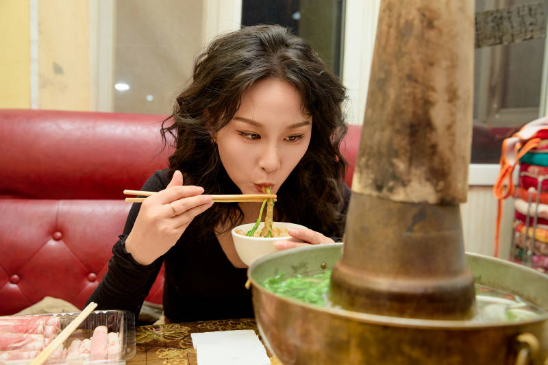 饭店吃传统铜锅涮肉的东方美女图片