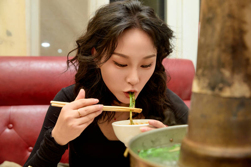 饭店吃传统铜锅涮肉的东方美女图片