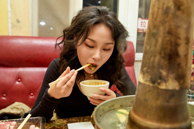 饭店吃传统铜锅涮肉的东方美女图片