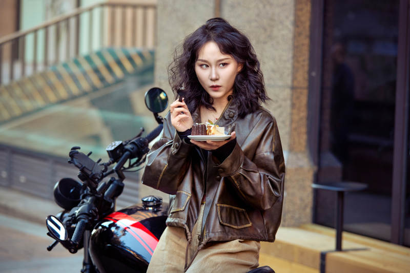 户外在复古机车上品尝甜点的亚洲美女图片