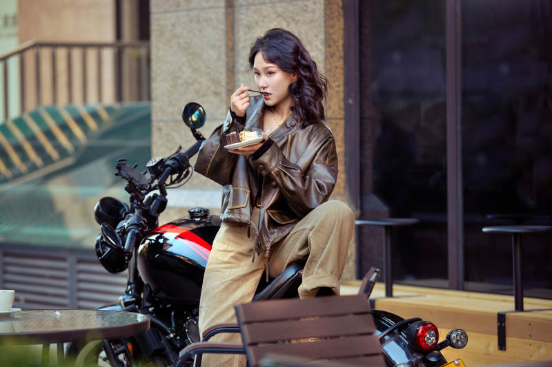 户外在复古机车上品尝甜点的亚洲美女图片