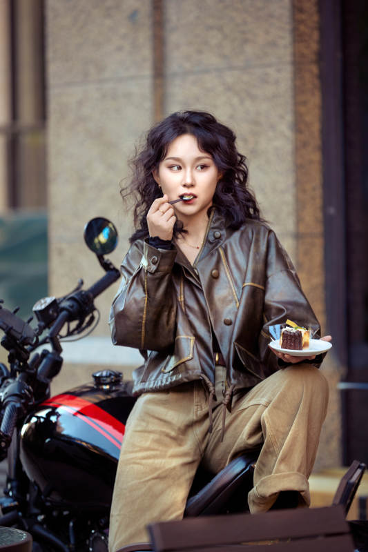 户外在复古机车上品尝甜点的亚洲美女图片