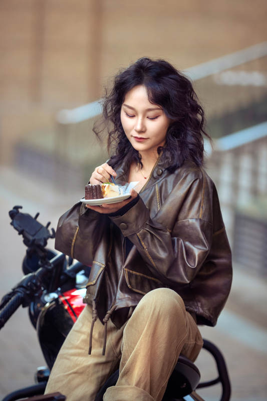 户外在复古机车上品尝甜点的亚洲美女图片