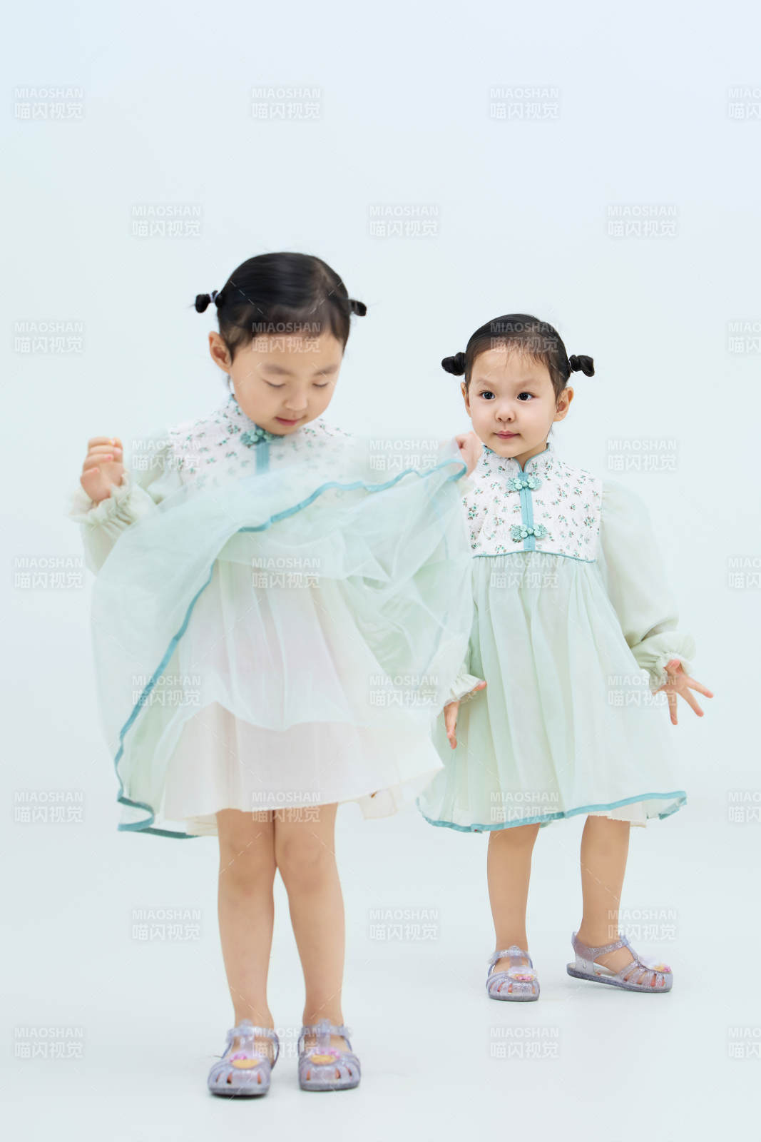 白色背景下顽皮可爱的双胞胎小女孩图片