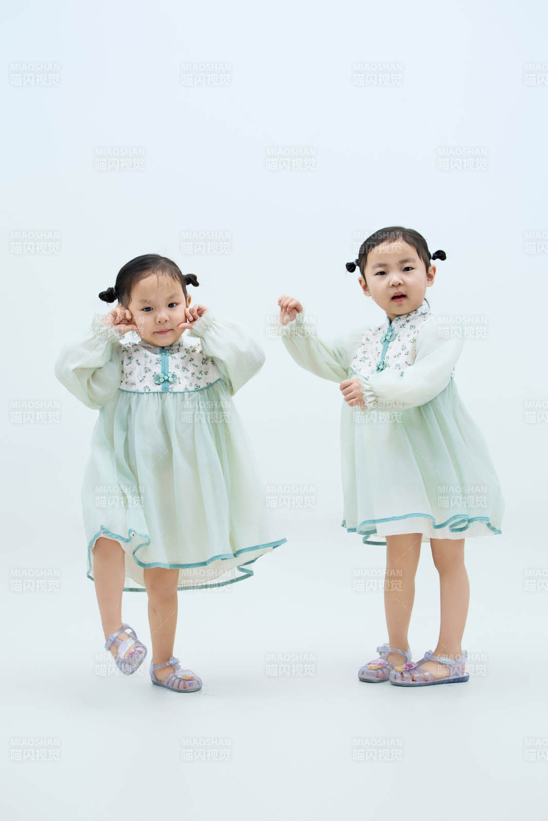 白色背景下顽皮可爱的双胞胎小女孩图片