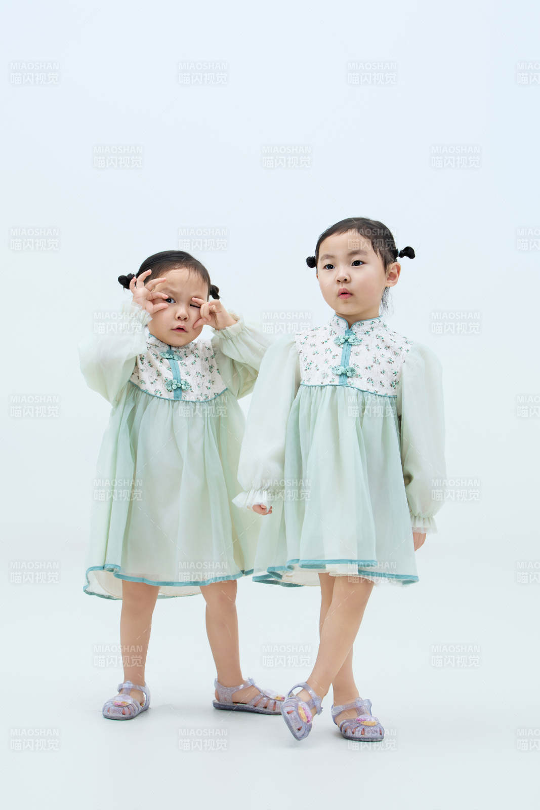 白色背景下顽皮可爱的双胞胎小女孩图片