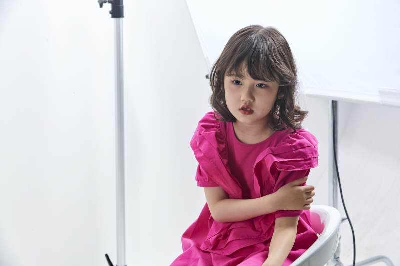 白色背景里坐在凳子上的可爱的亚洲小女孩儿童图片