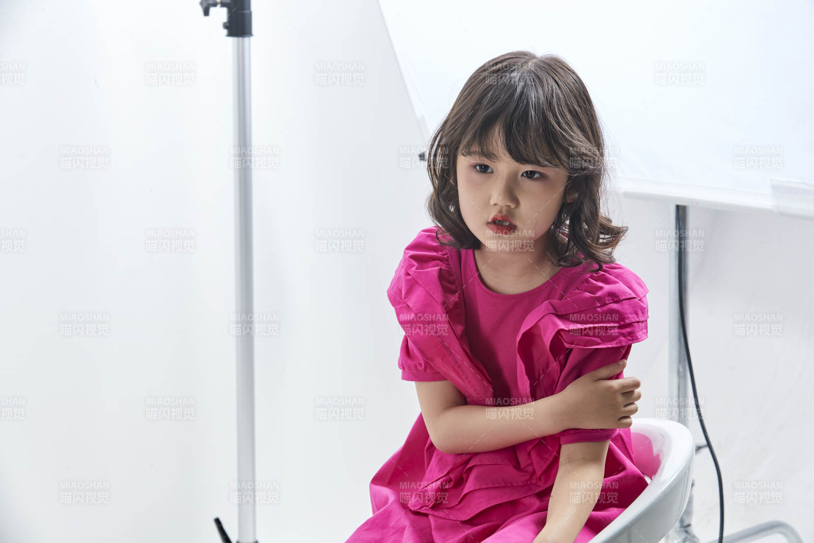 白色背景里坐在凳子上的可爱的亚洲小女孩儿童图片