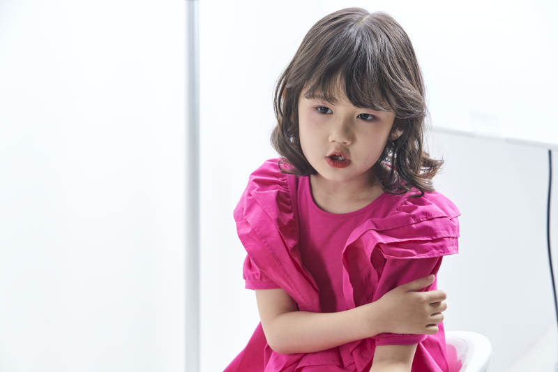 白色背景里坐在凳子上的可爱的亚洲小女孩儿童图片