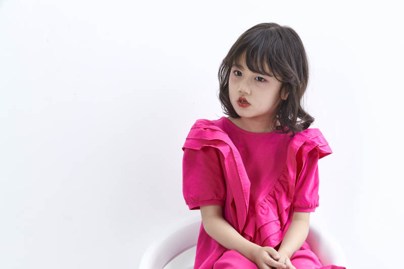 白色背景里坐在凳子上的可爱的亚洲小女孩儿童图片