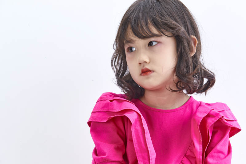 白色背景里坐在凳子上的可爱的亚洲小女孩儿童图片