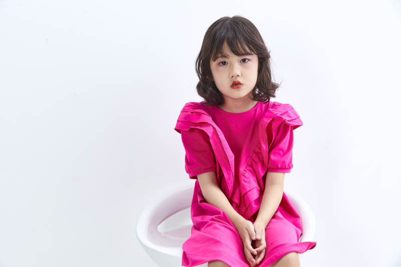 白色背景里坐在凳子上的可爱的亚洲小女孩儿童图片