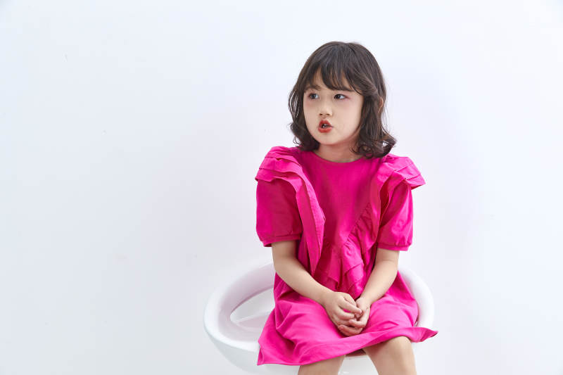 白色背景里坐在凳子上的可爱的亚洲小女孩儿童图片