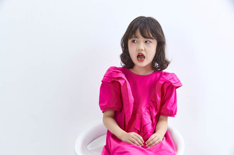 白色背景里坐在凳子上的可爱的亚洲小女孩儿童图片