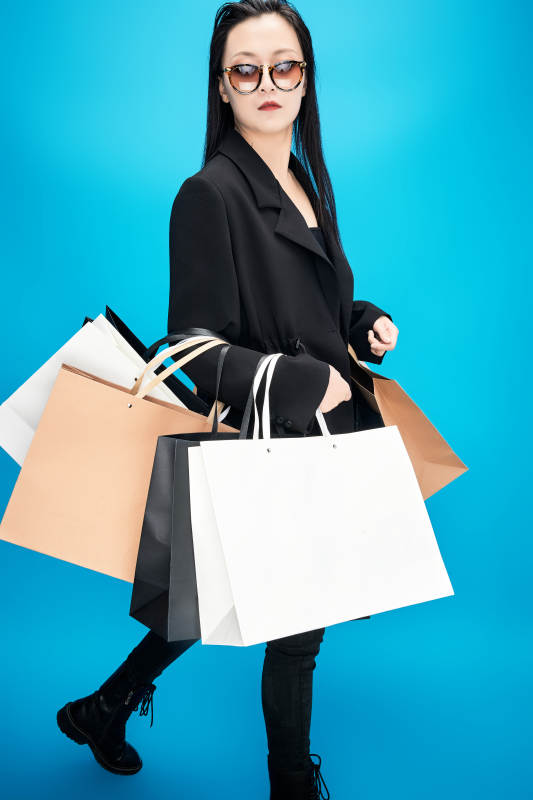 青蓝色背景下手提购物袋的亚洲时尚少女图片