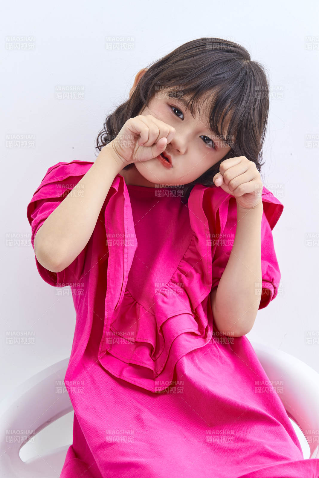 白色背景里坐在凳子上的可爱的亚洲小女孩儿童图片